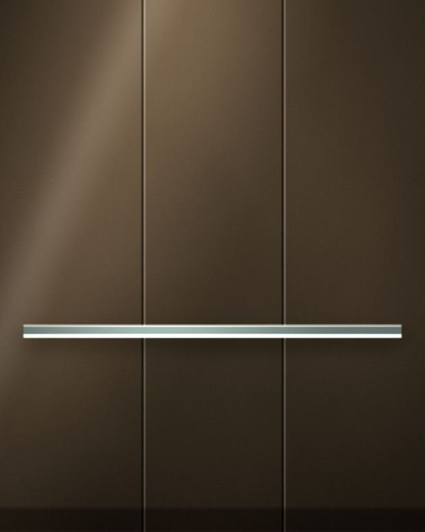 Bronze back-painted glass wall panels with fine open joints, crossed by a slim glass shelf whose polished edge catches the light.